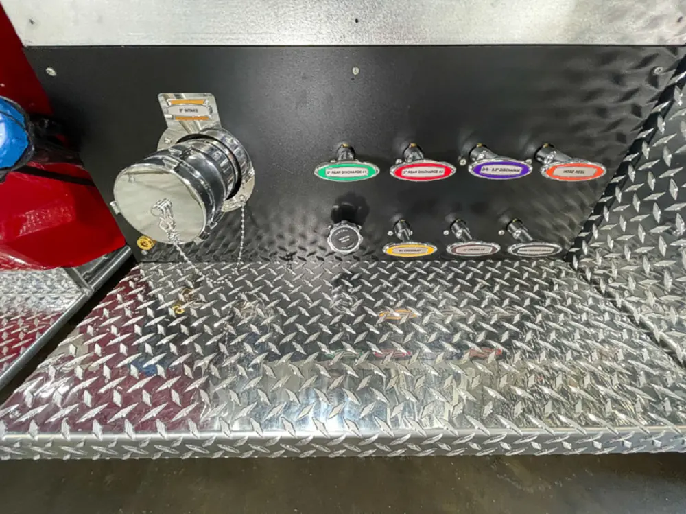 Exterior view of small fire truck showing cab, body compartments, and wheel/tire area.